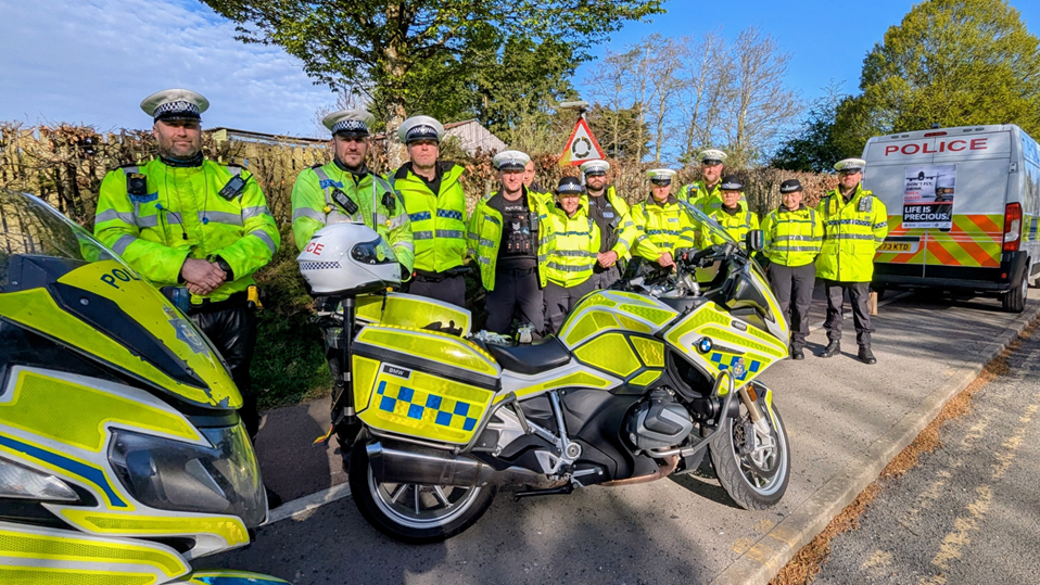 Officers lined up in front of a police bike