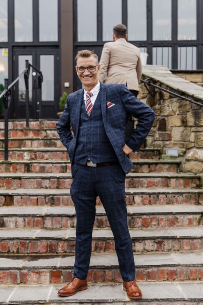 Kevin Wilson dressed in a smart blue suit standing on some stone steps