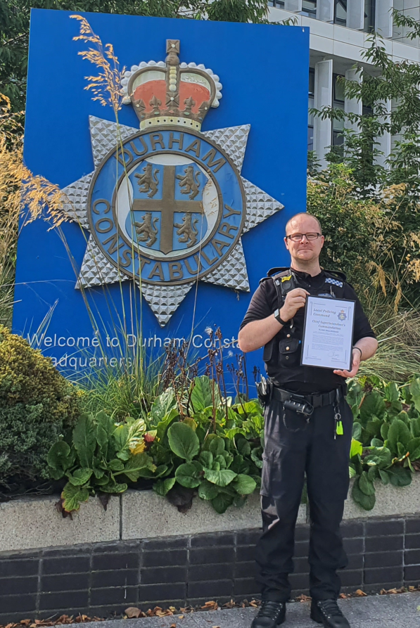 PC Hubbard with his commendation in front of the Durham Constabulary sign at HQ